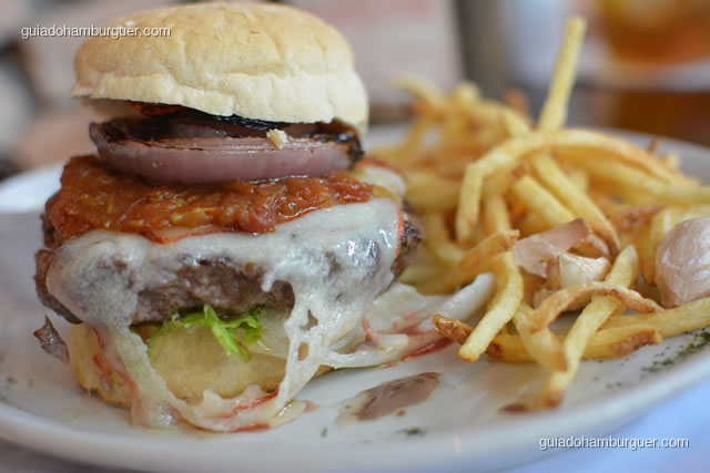 Detalhe do burger com queijo derretido, chutney de tomate e cebola na brasa - Pobre Juan